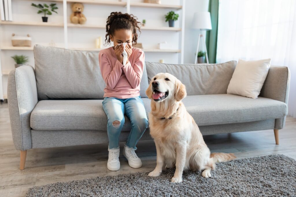 little girl blowing her nose next to a dog